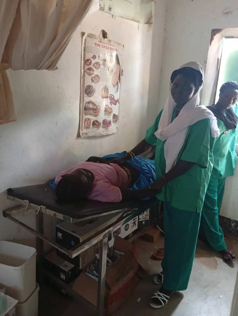 Two nurses in green scrubs attending to a patient in the delivery room